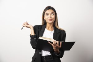 Young businesswoman writing in clipboard with pencil . High quality photo